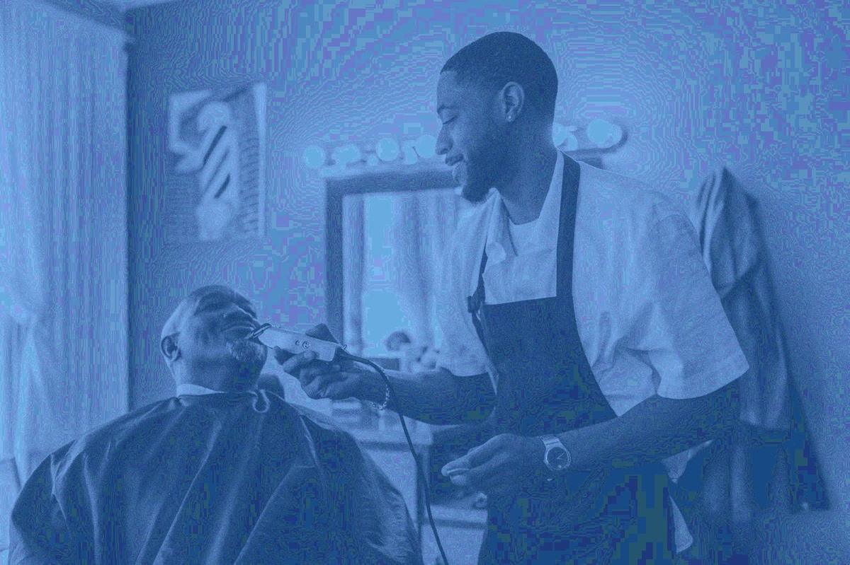 Barber trimming a client beard with clippers